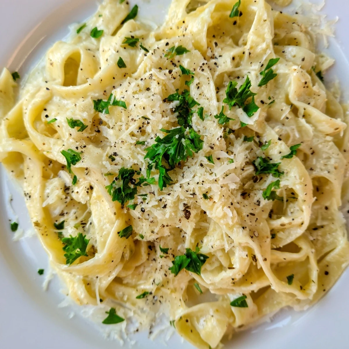 Creamy Sauce over Pasta served in a white bowl with fresh parsley and grated Parmesan, steam rising from the silky, garlic-infused sauce.