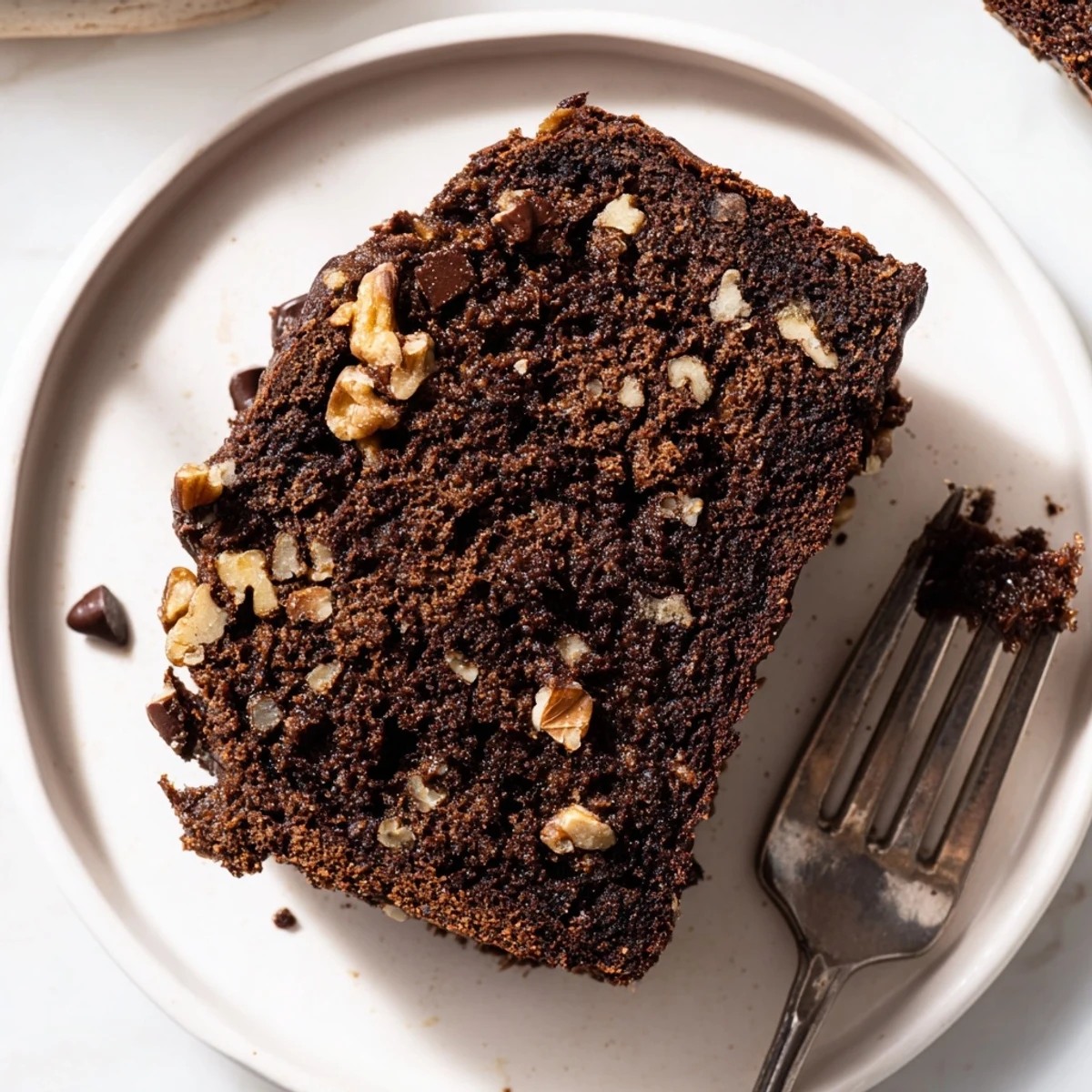 Freshly baked Chocolate Banana Bread loaf with melted chocolate chips visible on top and sides, served warm on a rustic wooden board.