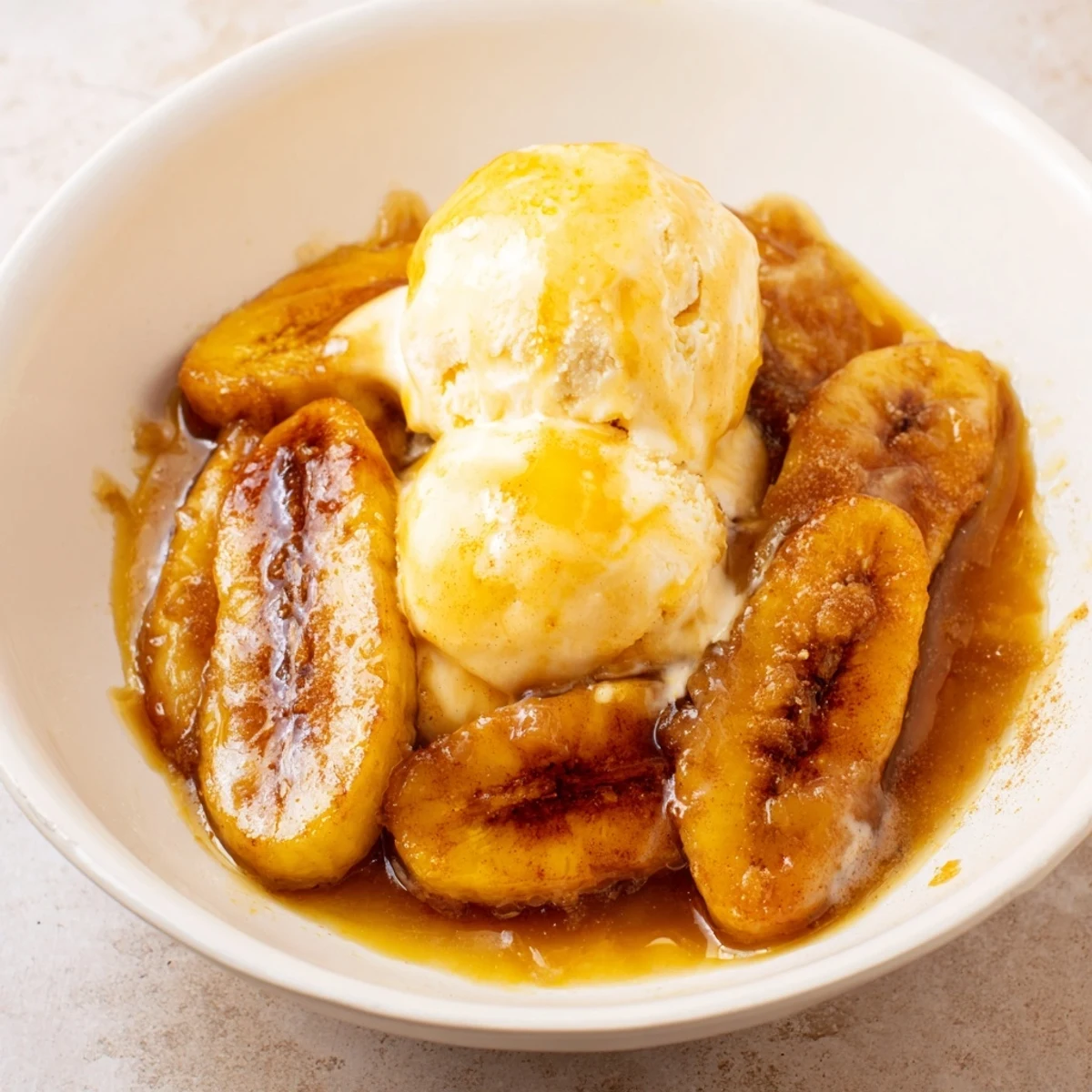 Warm, caramelized bananas in a rich brown sugar sauce top vanilla ice cream in this Classic Bananas Foster dessert.  