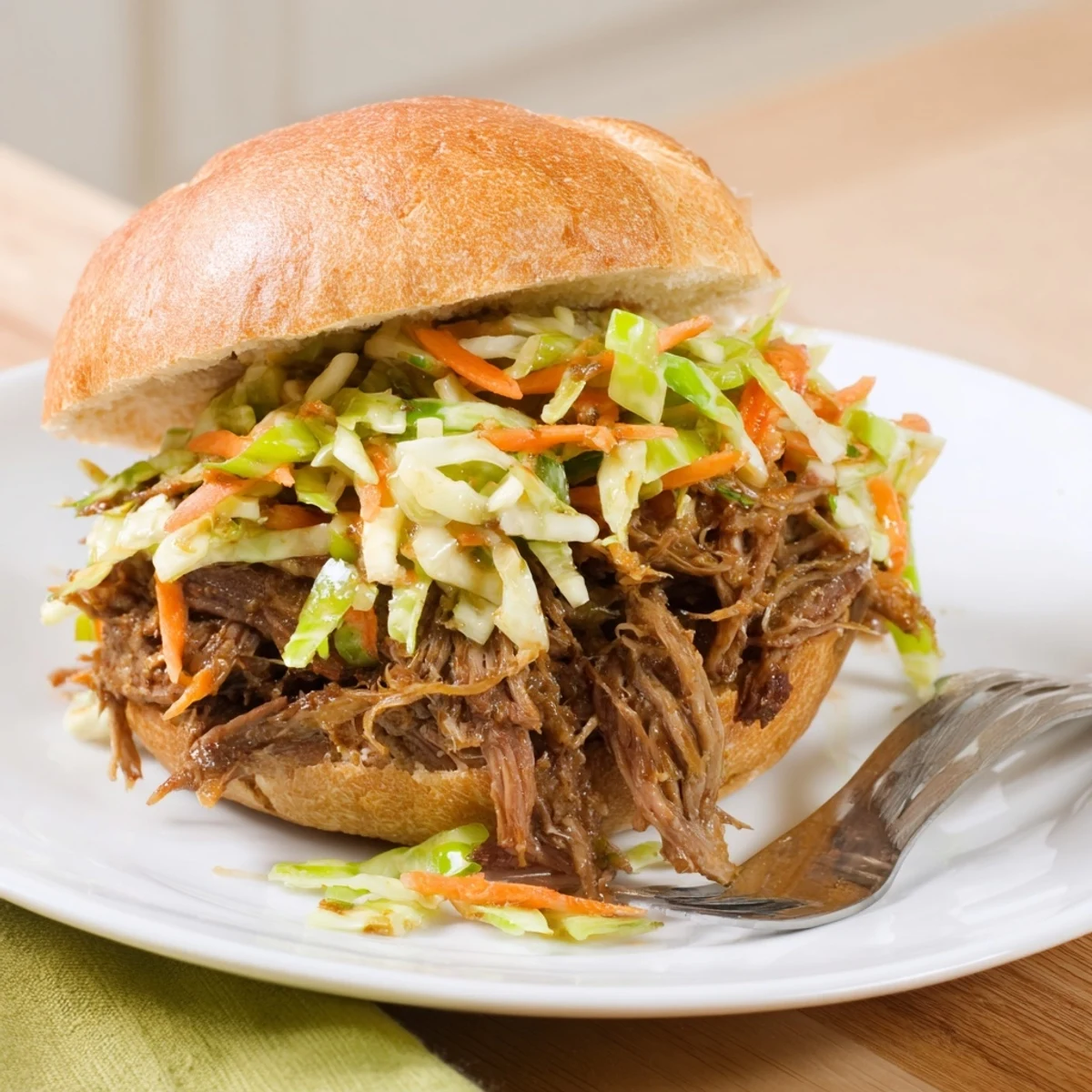 Shredded beef and crisp cabbage slaw topping on a toasted sandwich bun, ready to serve.