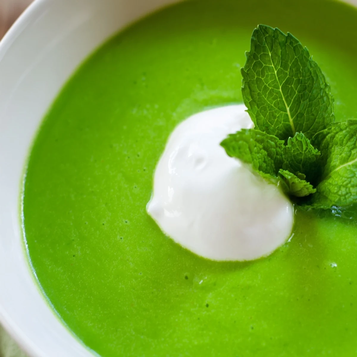 A vibrant bowl of Green Pea and Mint Soup served hot with crusty bread on the side for dipping.  