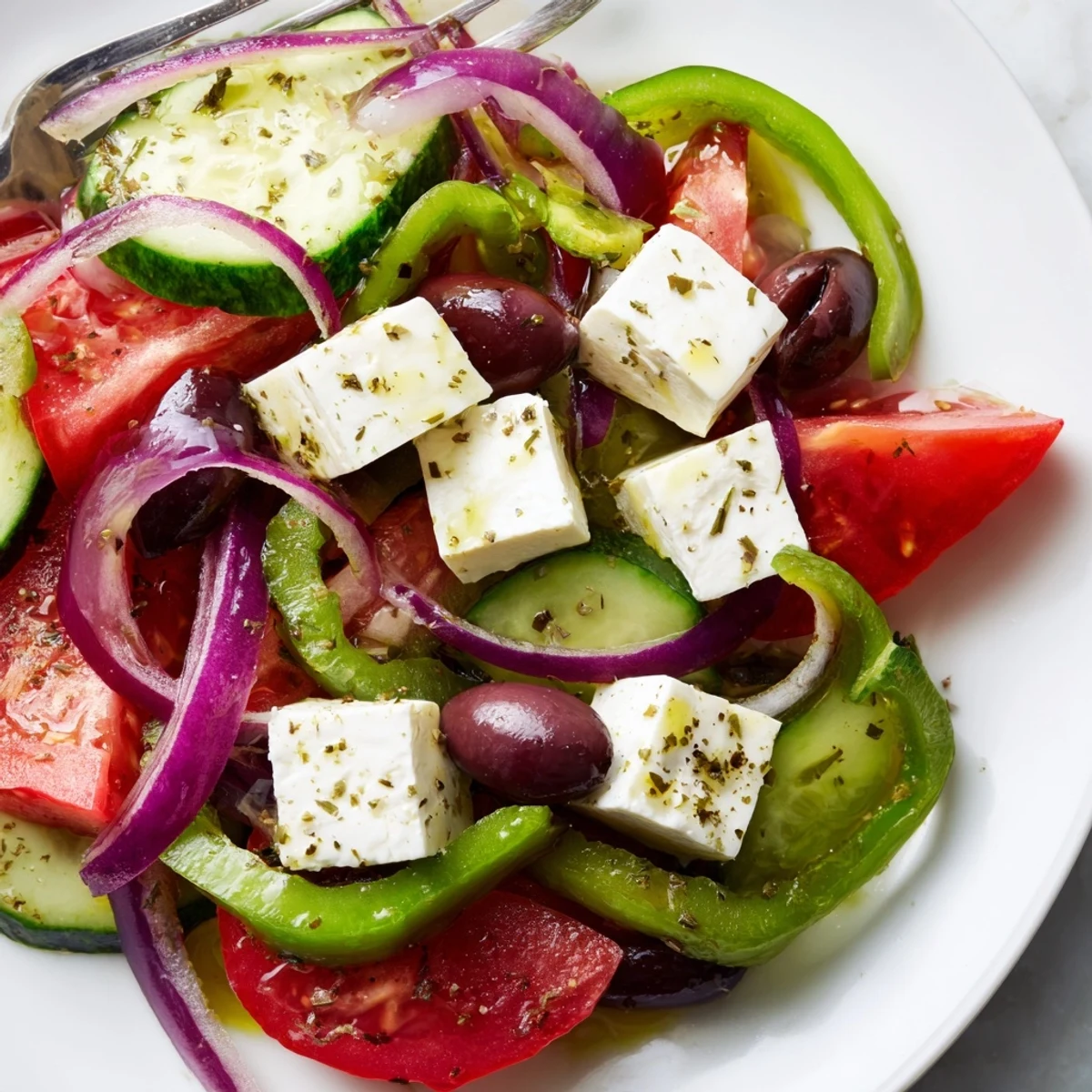 Fresh Greek salad with Kalamata olives and feta, featuring crisp tomatoes, cucumbers, and red onion in a light vinaigrette.