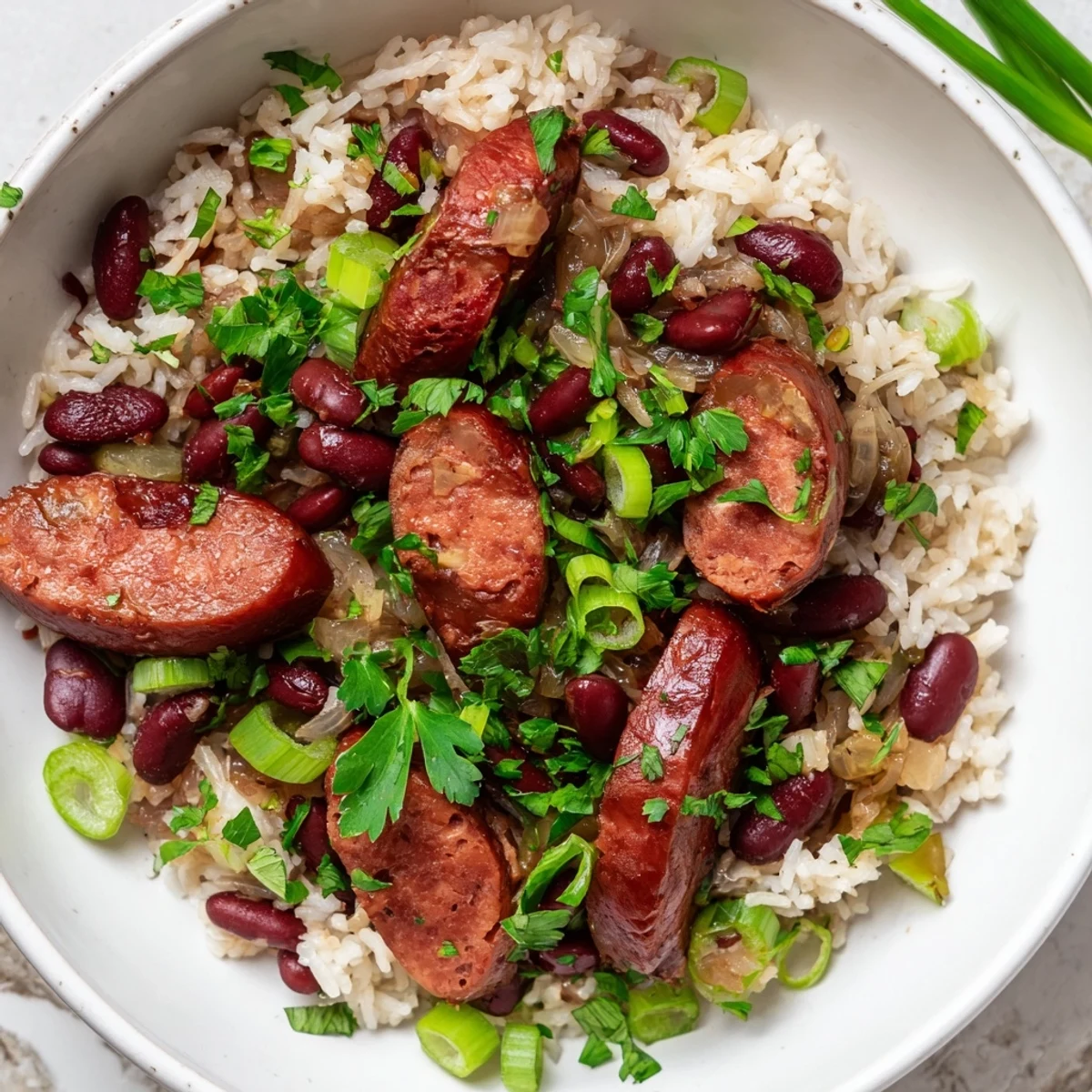 Spicy Mardi Gras Rice and Beans with Beef Sausage in a festive bowl, topped with green onions.