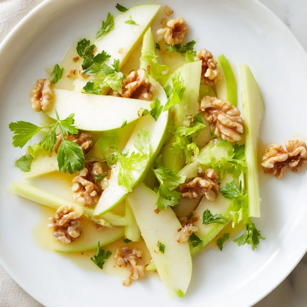 Bright bowl of Apple and Celery Salad with Walnuts tossed with chopped parsley, ready to serve as a refreshing American side or starter.