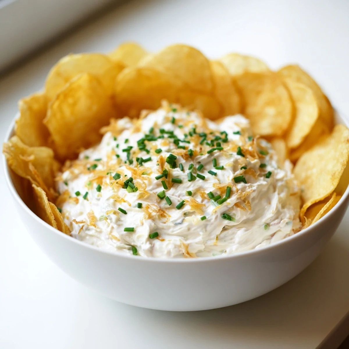 Rich onion dip with crispy potato chips perfect for game day snacking or party appetizers.