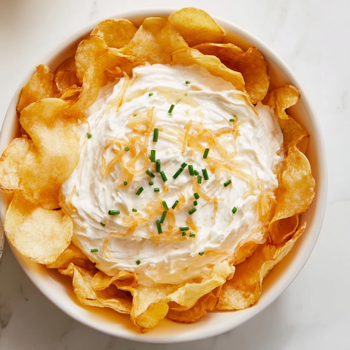 Fresh chives garnish this creamy savory onion dip served with golden potato chips for dipping.
