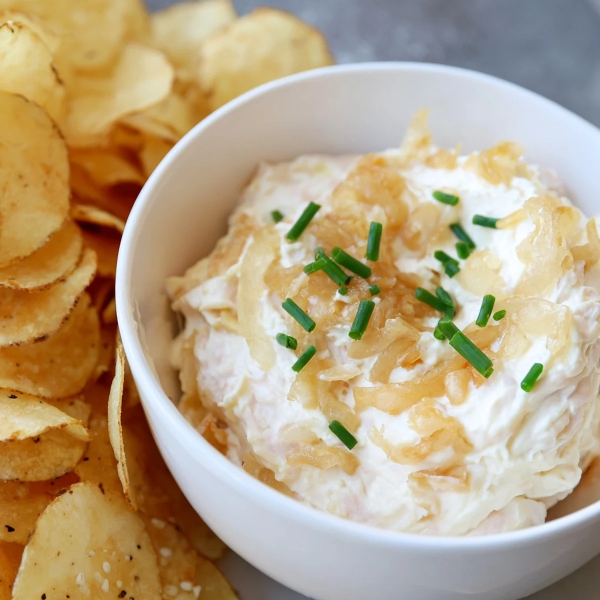 Savory party snack of warm onion dip with crunchy potato chips, perfect for game day gatherings.