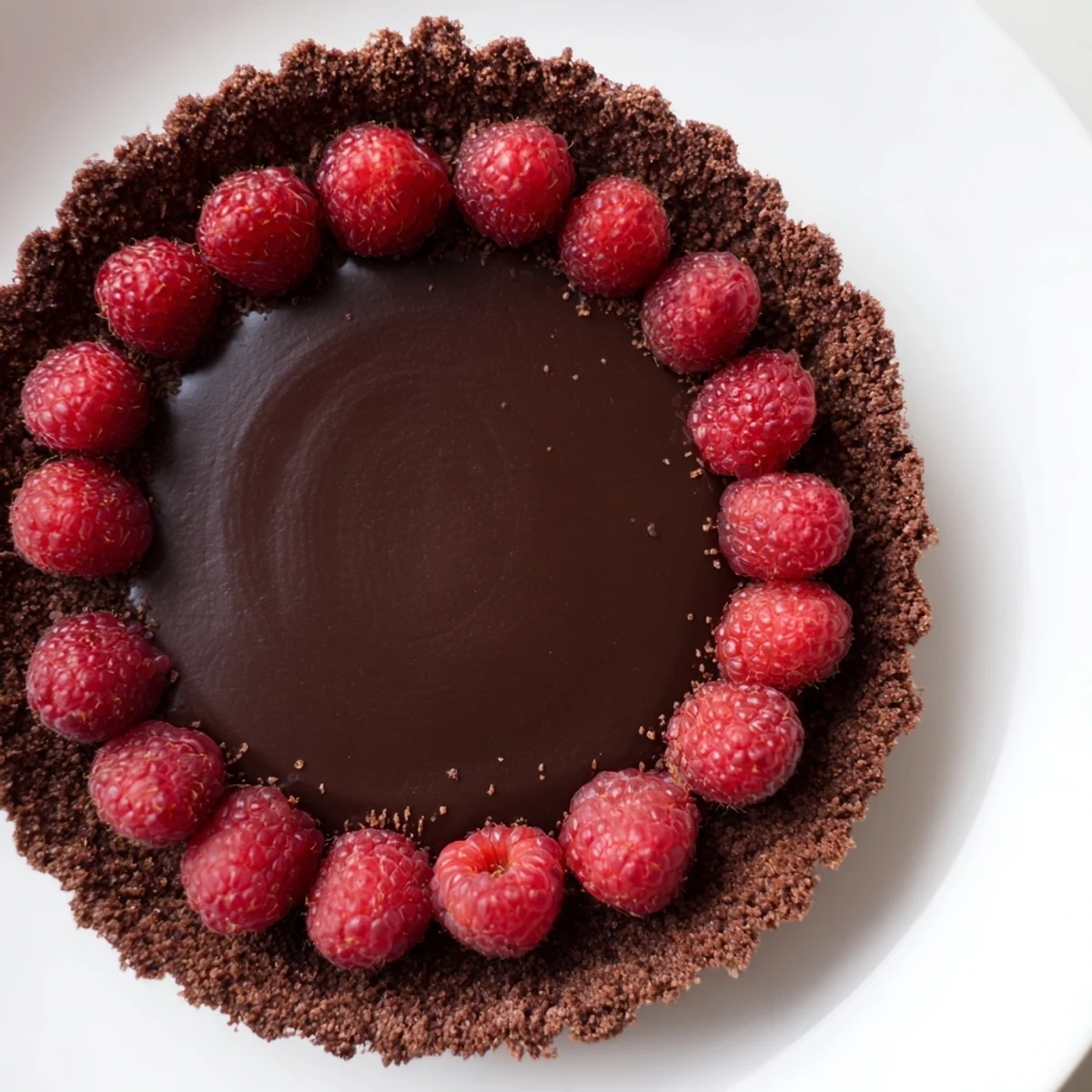 An inviting image of chocolate raspberry tart served on a rustic wooden table, garnished with ripe raspberries and ready for a sweet indulgence.