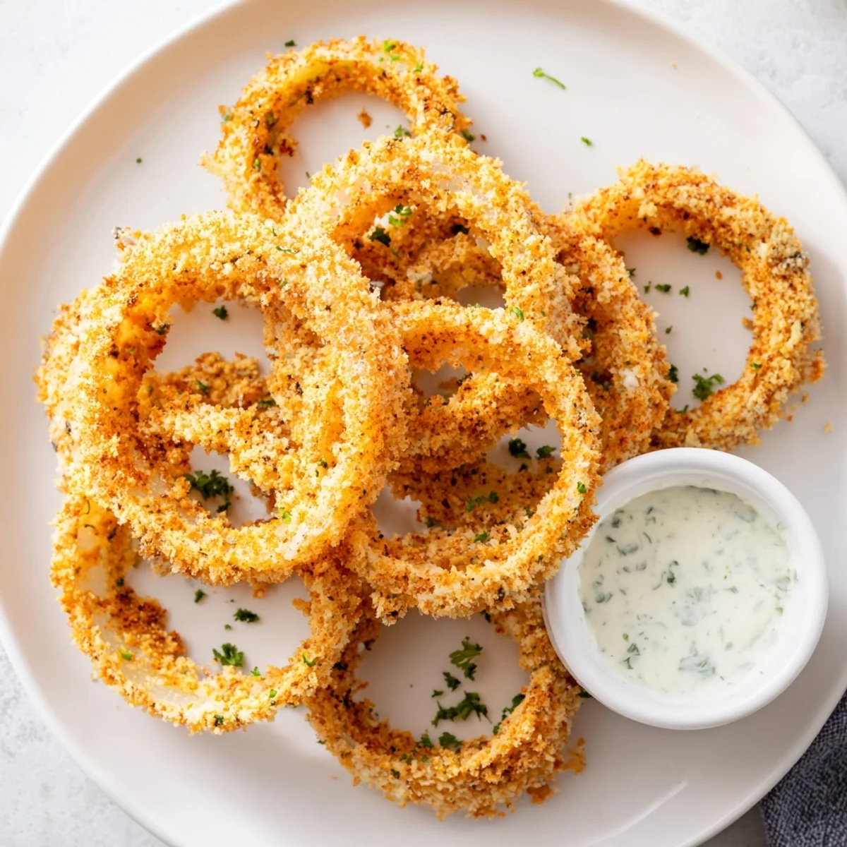 Golden Crispy Baked Onion Rings with Ranch arranged on a platter with creamy dip, ready to serve as a tasty snack.