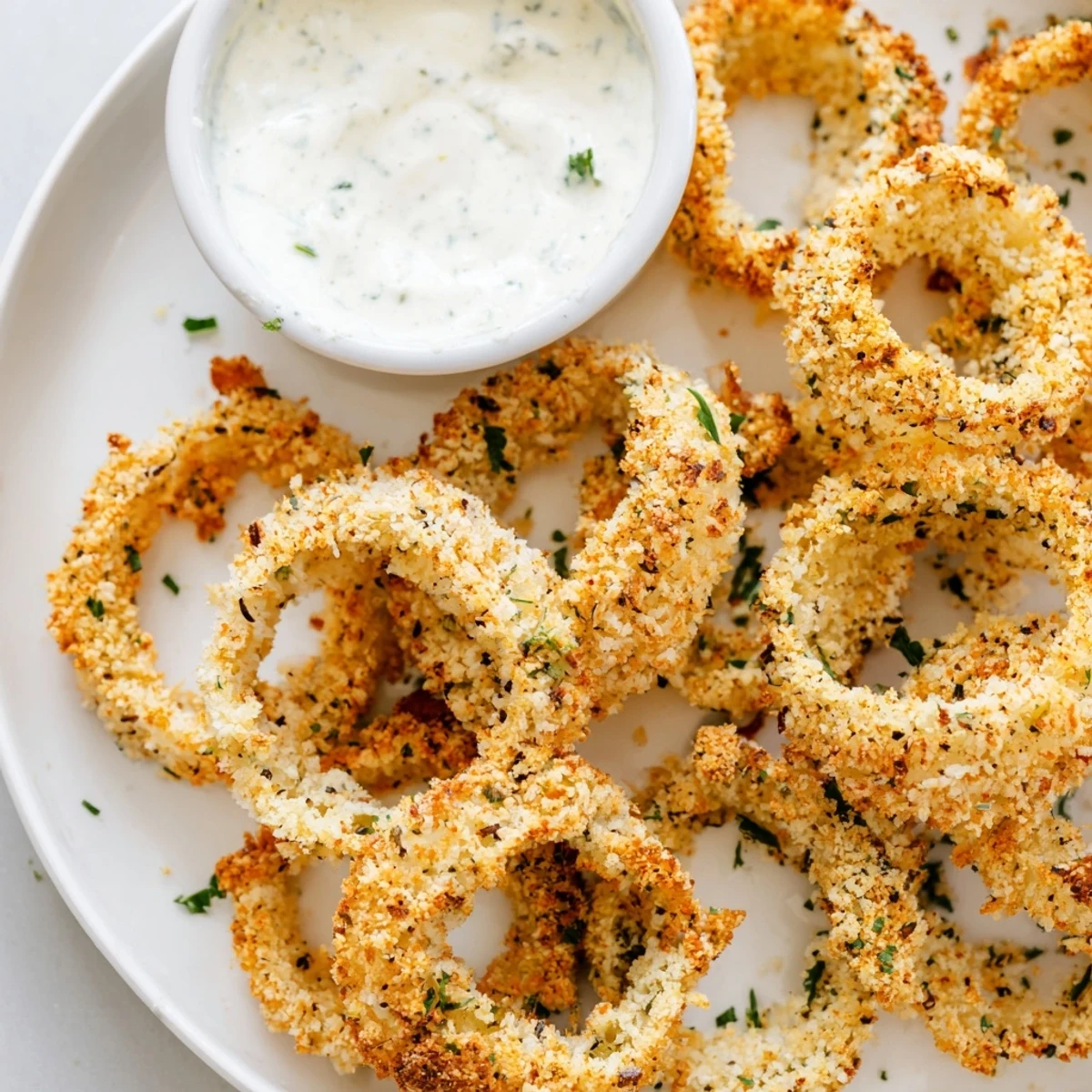 Freshly baked Crispy Baked Onion Rings with Ranch offer a crunchy texture and savory flavor, paired with a herb-filled ranch dip.