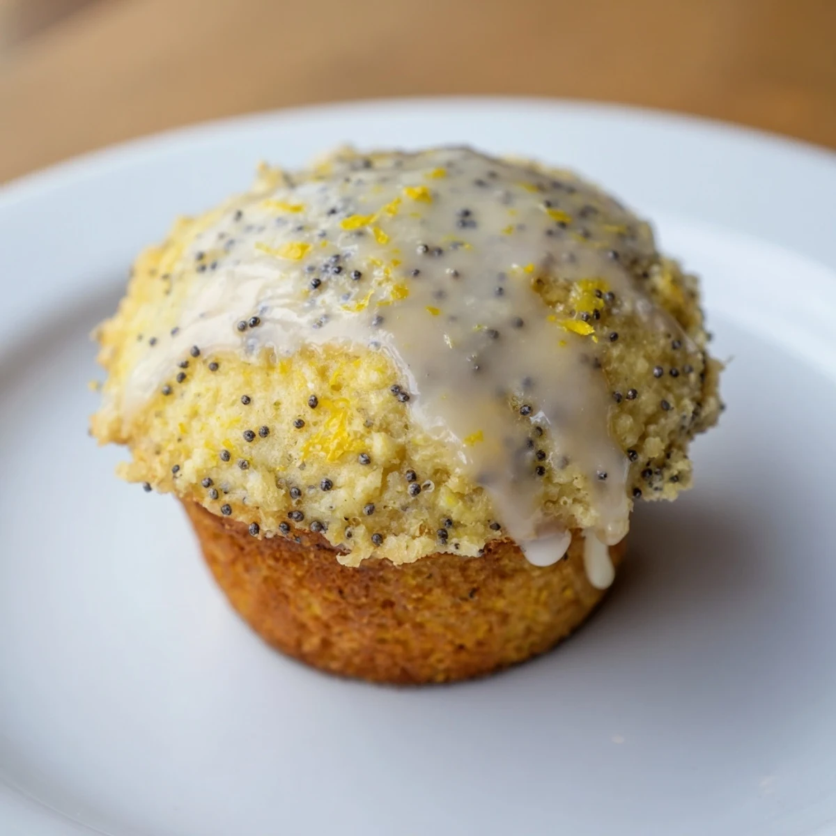 Freshly baked Lemon Poppy Seed Muffins with a glossy lemon glaze drizzled over the tops on a cooling rack.