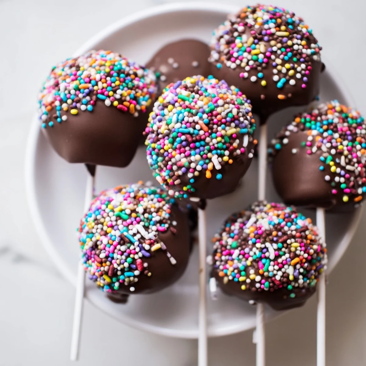 A close-up view of Chocolate Dipped Marshmallows with Sprinkles, highlighting glossy melted chocolate and festive sugary decorations.