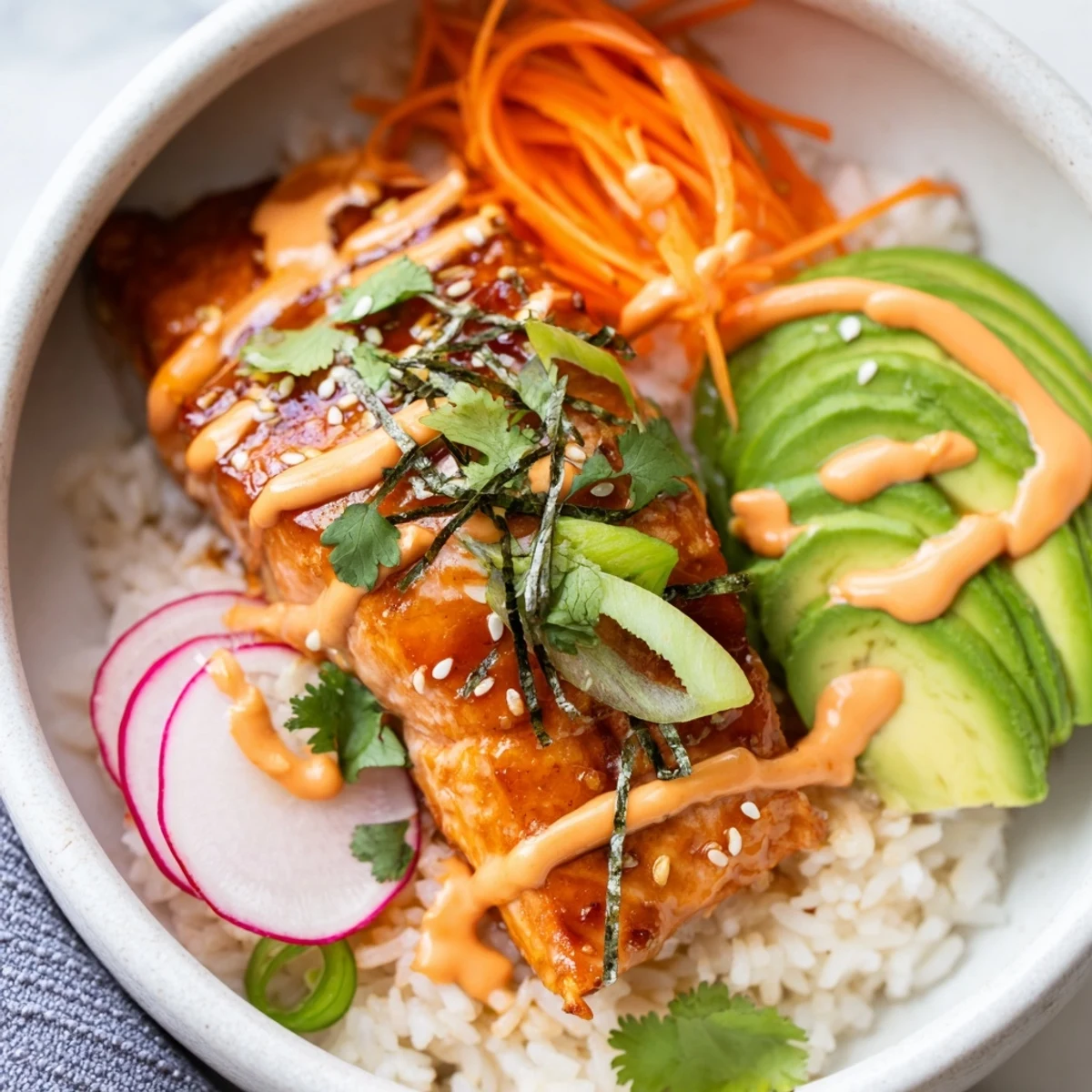 Colorful teriyaki salmon rice taco bowl garnished with fresh avocado, scallions, sesame seeds, and optional nori strips for crunch.