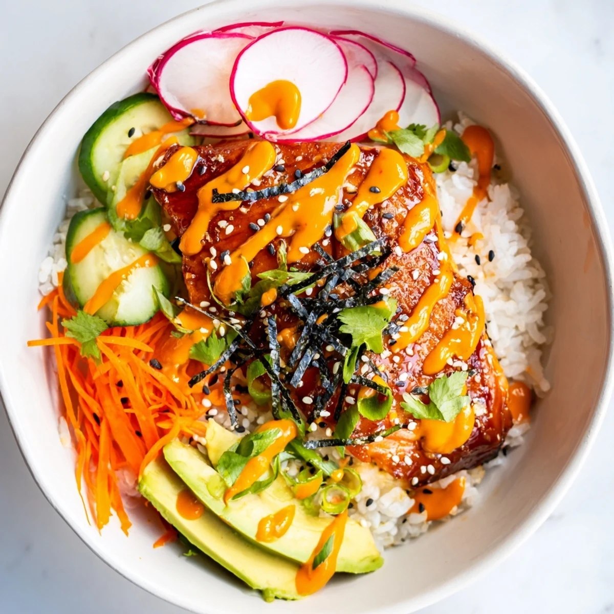 A vibrant fusion bowl with tender salmon, quick-pickled carrots and radishes, zesty sriracha mayo, and a sweet-savory teriyaki glaze.