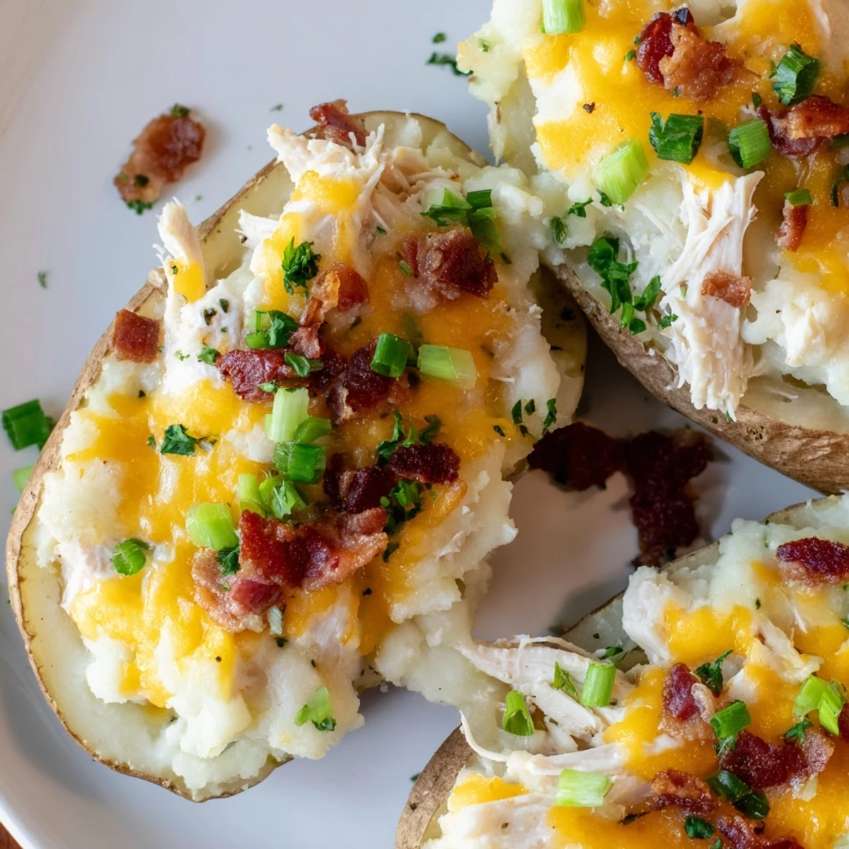 Hearty gluten-free Mud Chicken Stuffed Twice Baked Potatoes served hot, garnished with green onions and bacon bits.