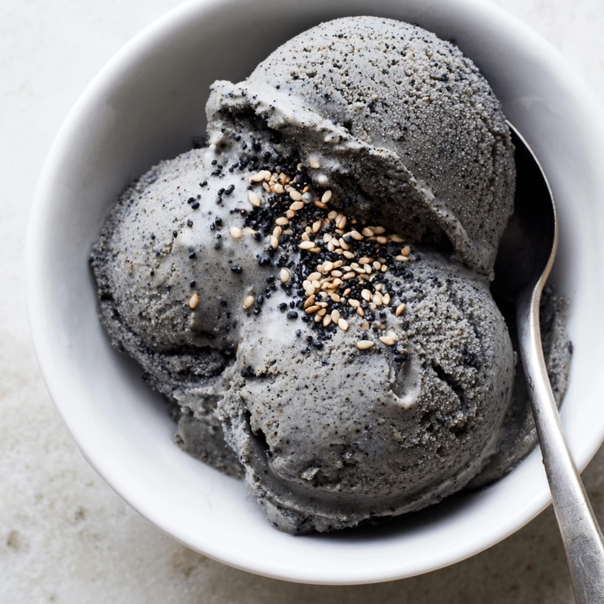 Homemade toasted black sesame ice cream served in a vintage dish with a drizzle of honey.