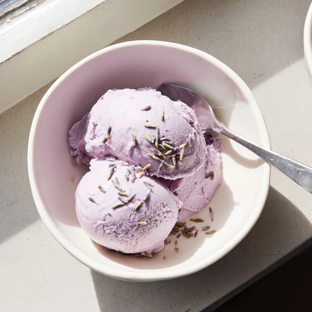 Lavender Ice Cream scoops feature a rich purple hue and are topped with fresh edible flowers.