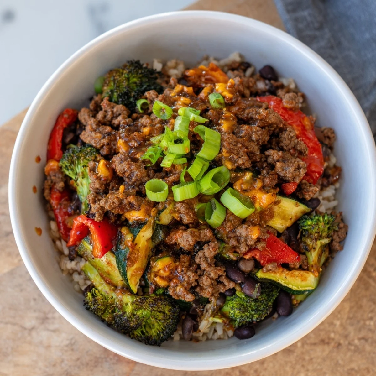 Hearty Viral Hot Honey Ground Beef Bowl features tender meat, roasted vegetables, sliced avocado, and green onions on a wholesome grain base.