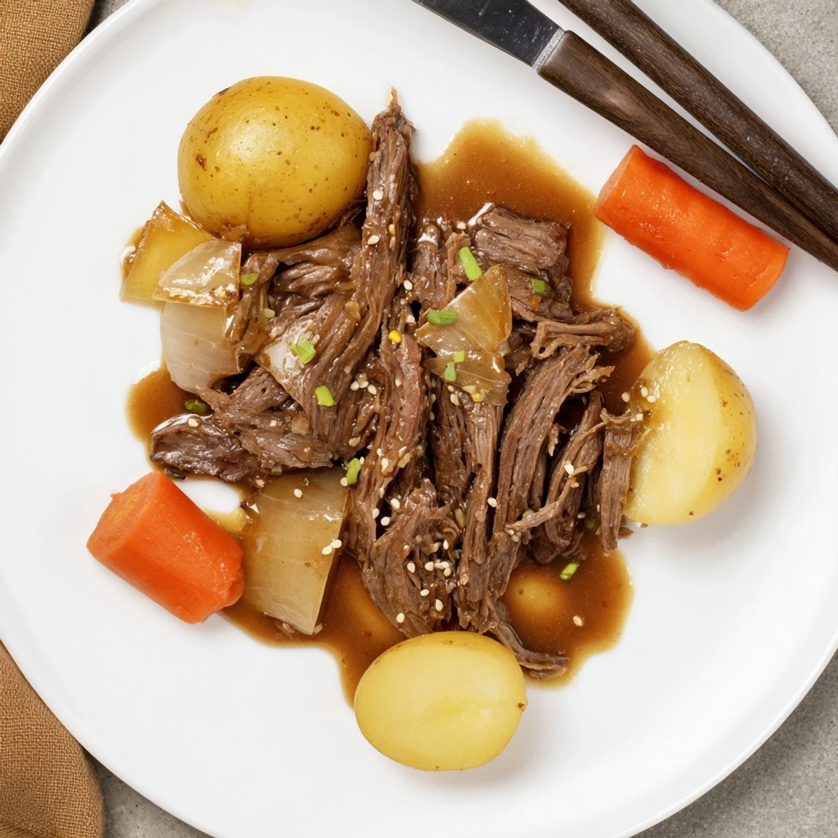 Hearty Slow Cooker Korean Beef Pot Roast With Soy Garlic Gravy garnished with scallions and sesame seeds.