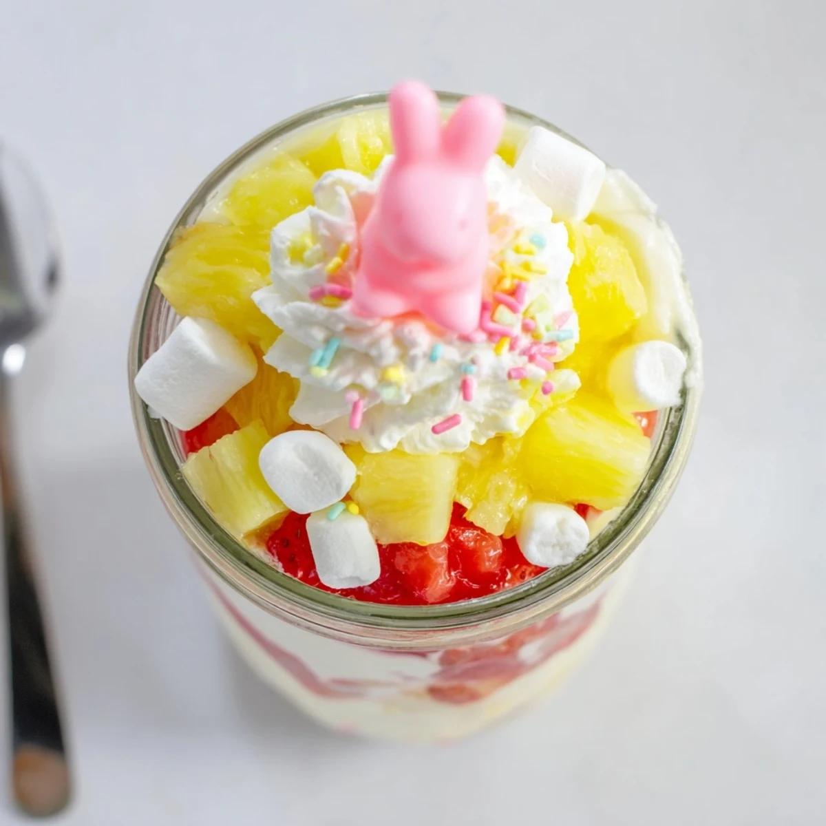 A single serving of Jello Pie Easter Bunny Parfait In A Jar topped with a marshmallow bunny and sprinkles.