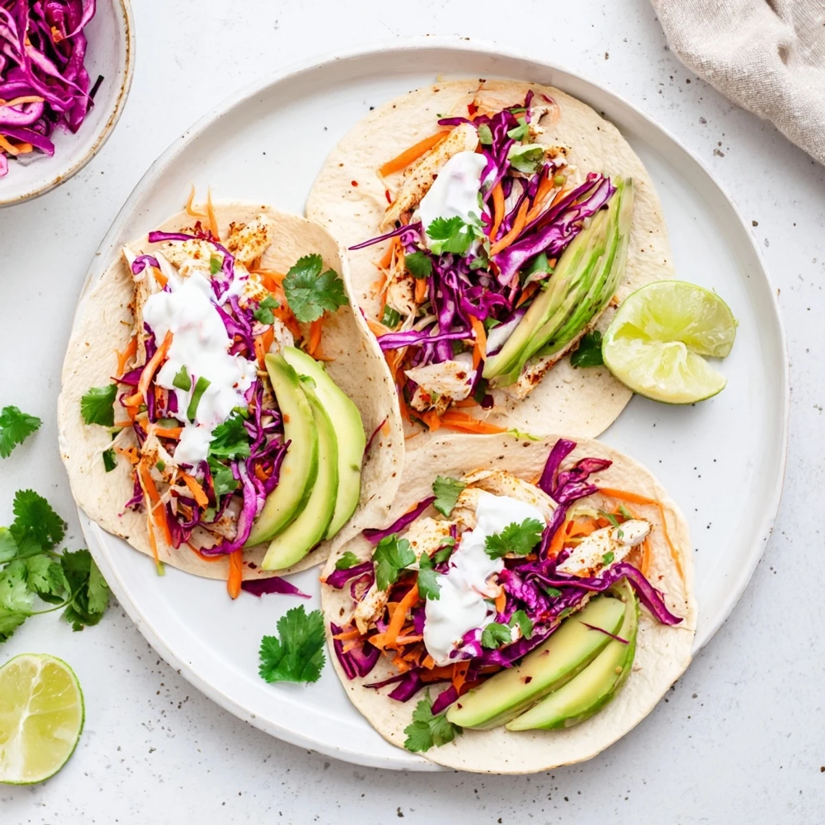 Serving suggestion shows four Aussie Barra Tacos on a rustic plate with lime wedges and sour cream dollops.