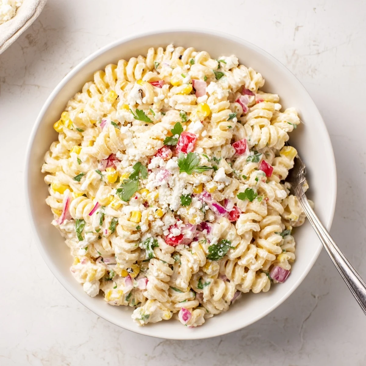 Colorful bowl of Mexican Street Corn Pasta Salad topped with cheese and jalapeño peppers