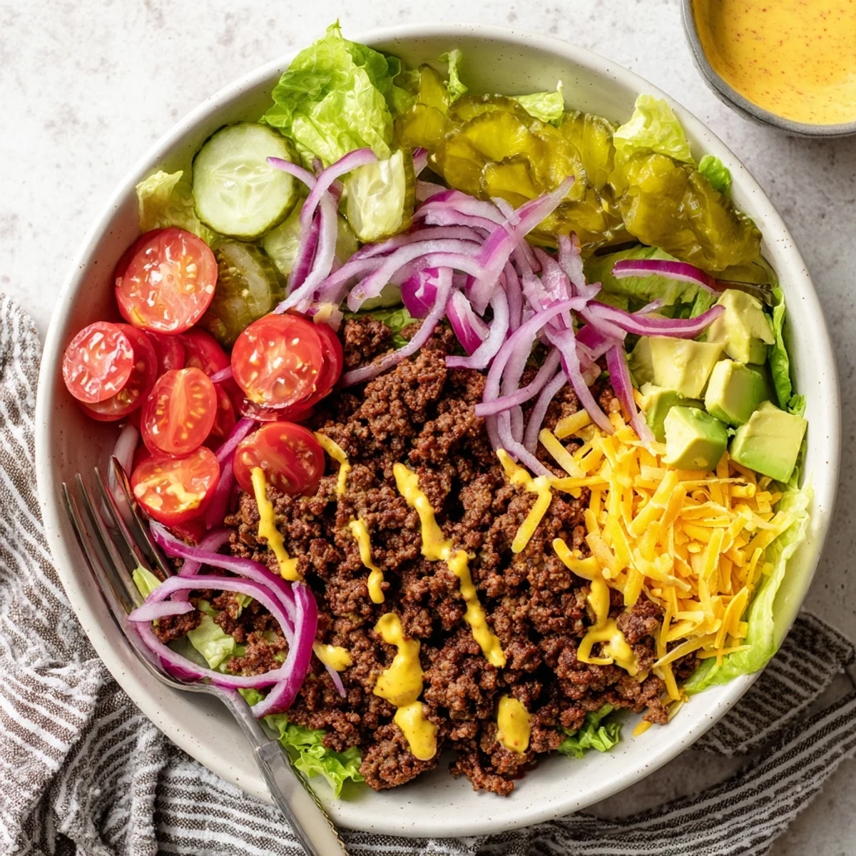 Colorful burger bowl with seasoned ground beef, fresh lettuce, tomatoes, cheese, and creamy burger sauce drizzled on top