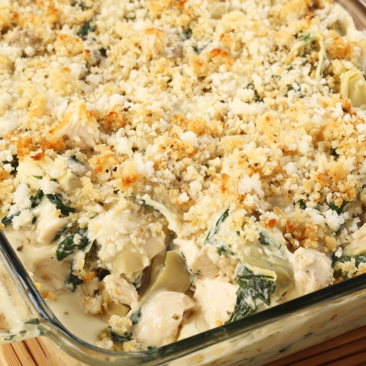 Creamy high protein casserole featuring tender chicken pieces, green spinach, and artichoke hearts topped with golden parmesan breadcrumbs