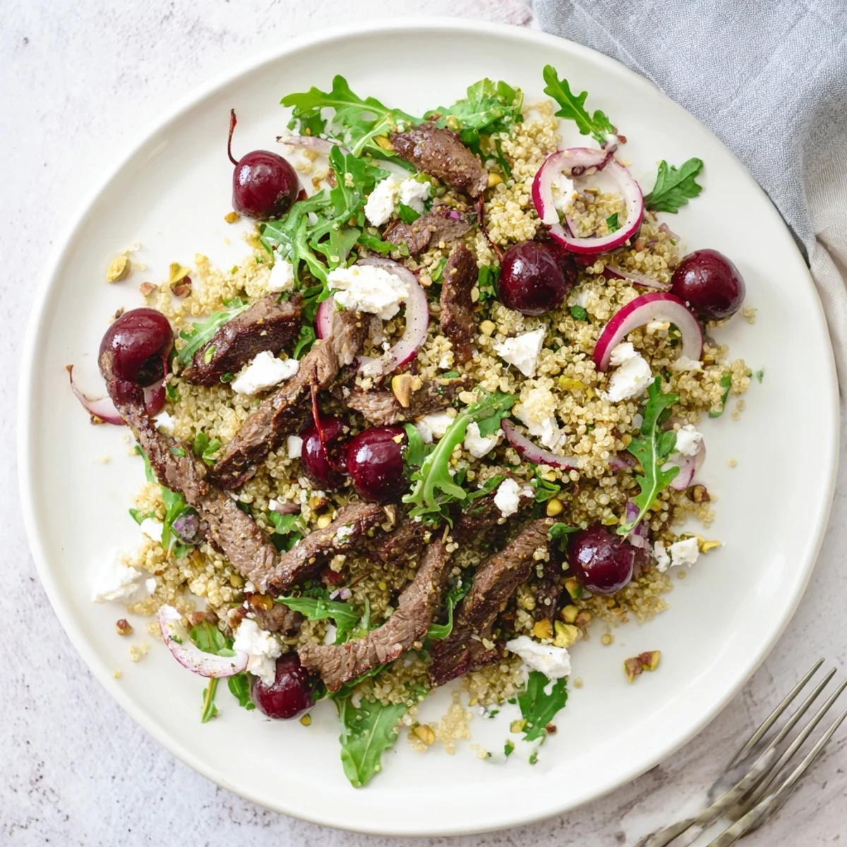 Summer salad plate with juicy cherries grilled lamb fluffy quinoa and vibrant green spinach leaves