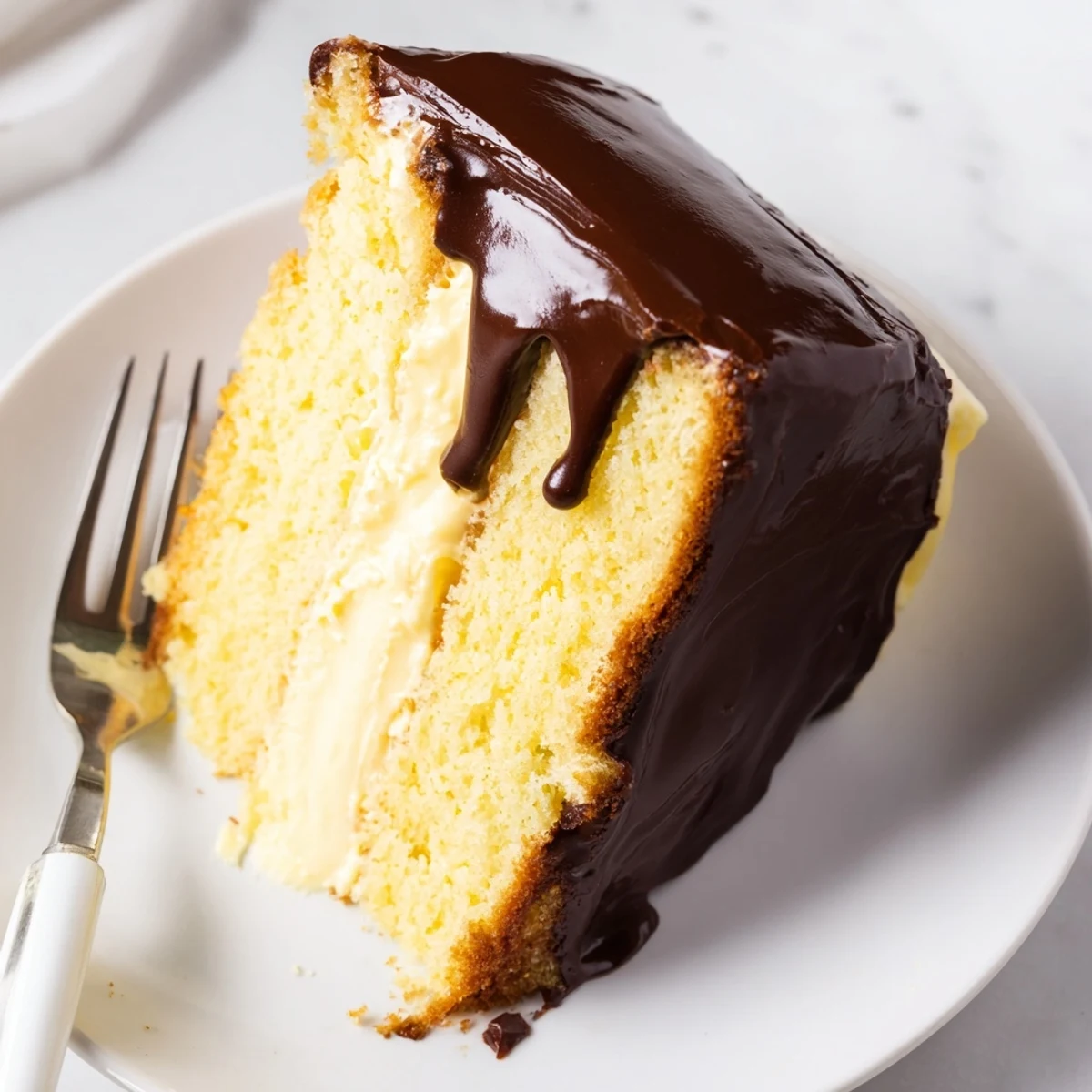 Golden Boston Cream Pie sliced to reveal velvety vanilla custard between moist sponge layers