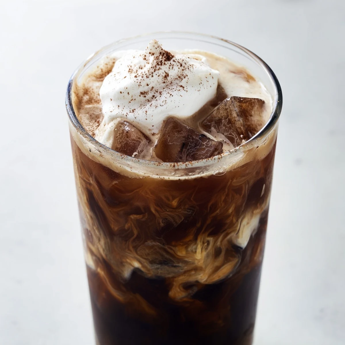 Creamy refreshing iced coffee served in tall glass with milk and ice cubes