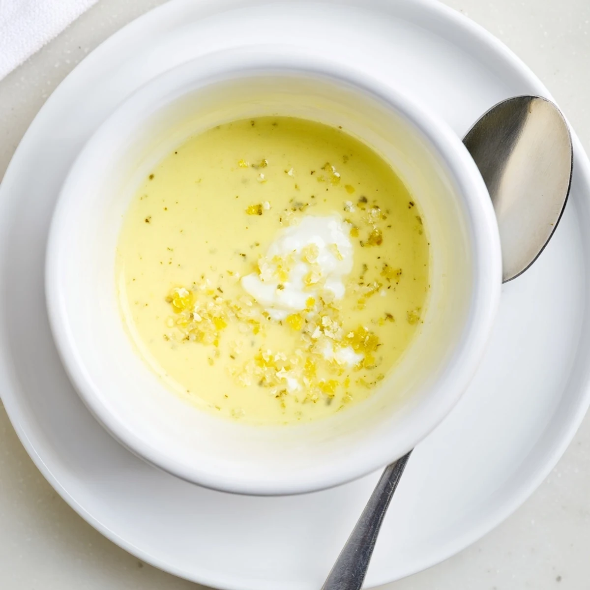 Drizzled creamy lemon vinaigrette coating crisp mixed greens in a white serving bowl