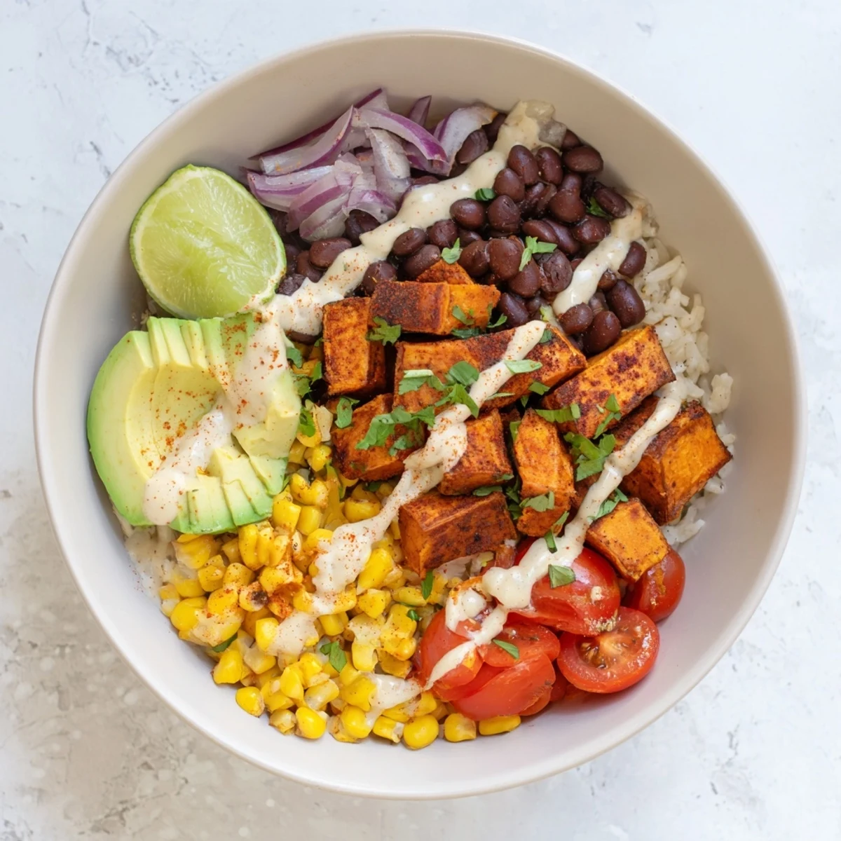 Mouthwatering vegan sweet potato burrito bowl layered with spiced roasted potatoes, seasoned black beans, and vibrant vegetable toppings