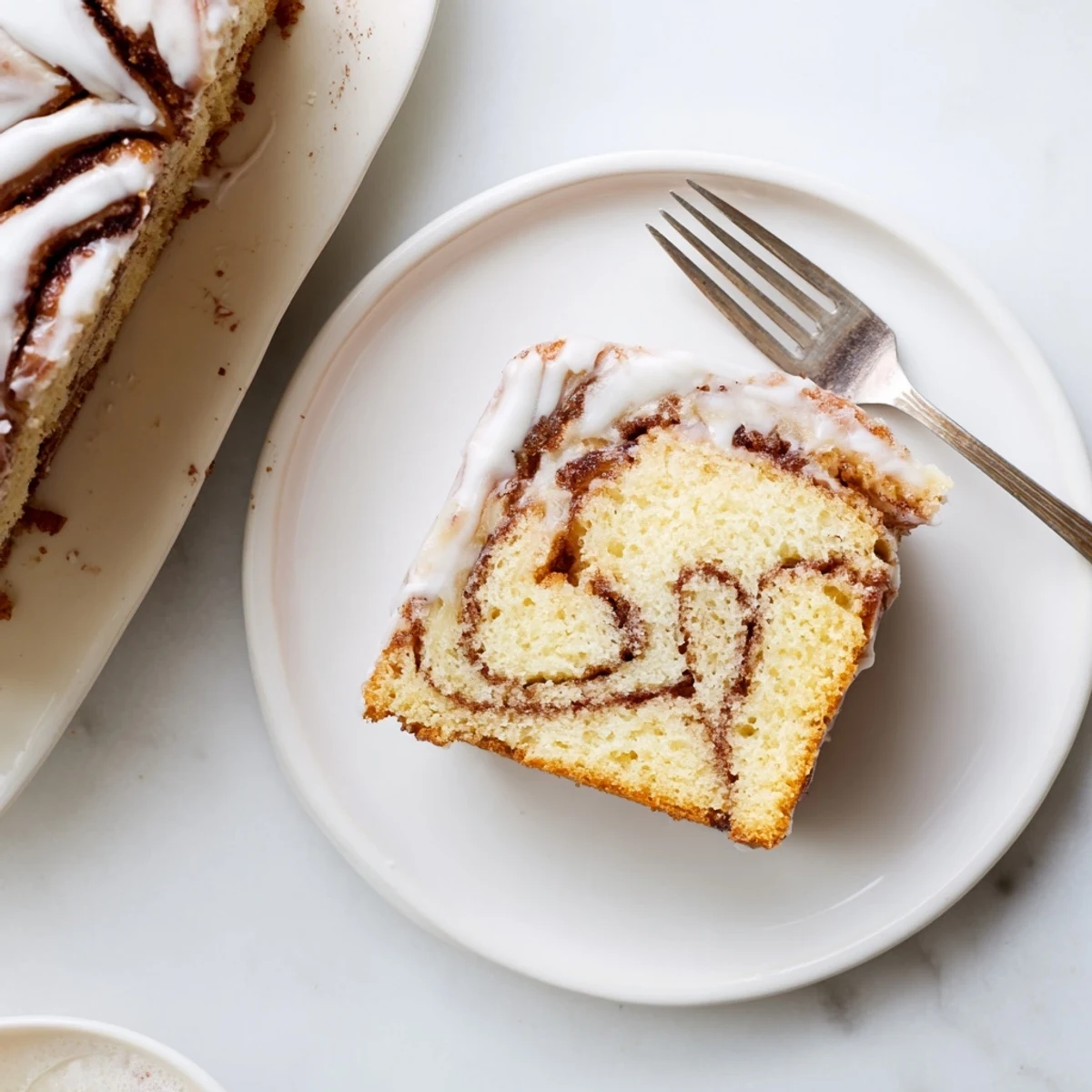 Golden cinnamon roll cake with swirling brown sugar ribbons drizzled with white vanilla glaze