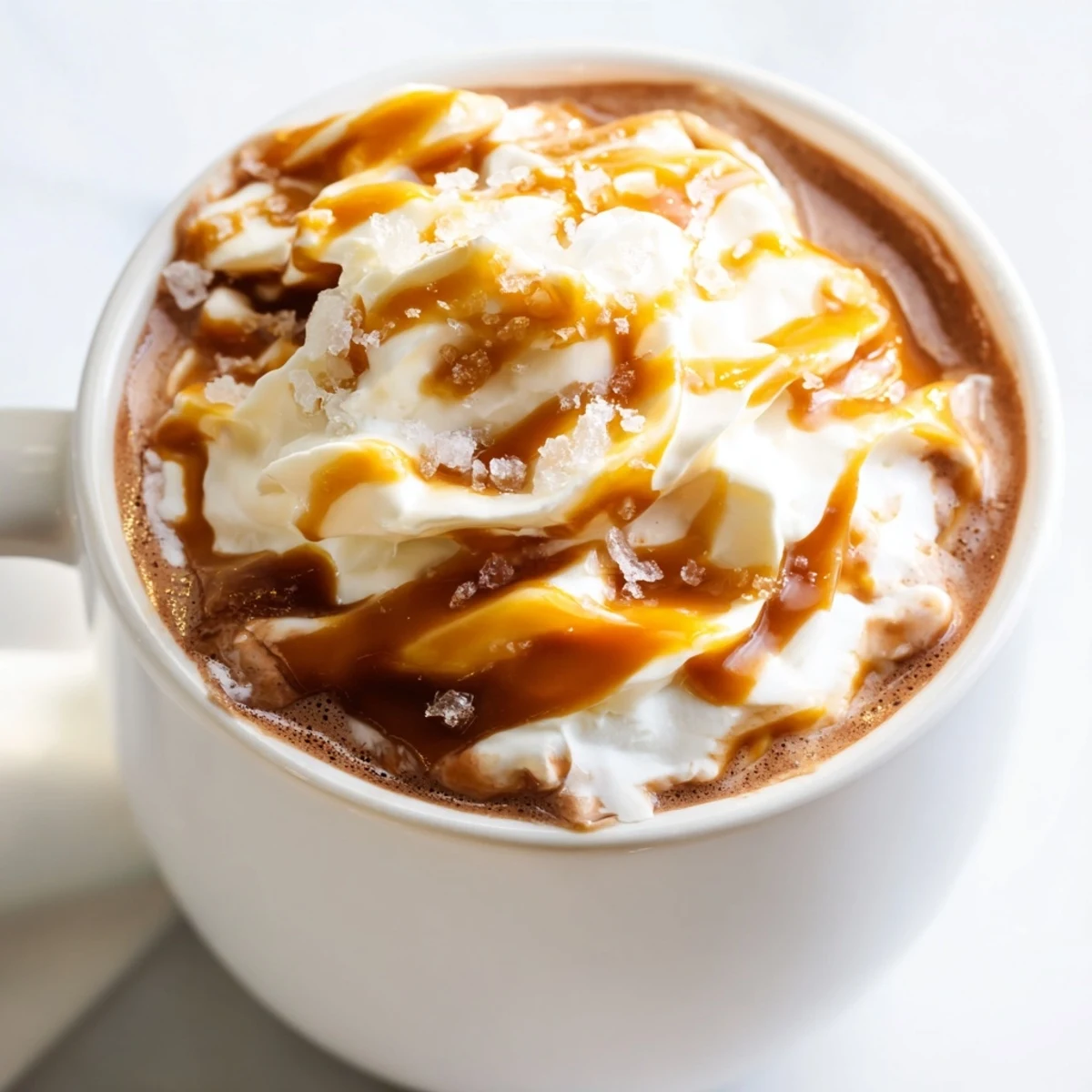 Creamy salted caramel hot chocolate topped with whipped cream and caramel drizzle in a mug