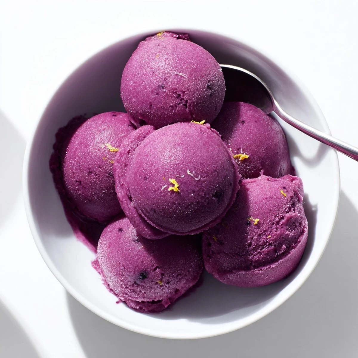 Bright purple no churn blueberry lemon sorbet scooped into a chilled glass bowl