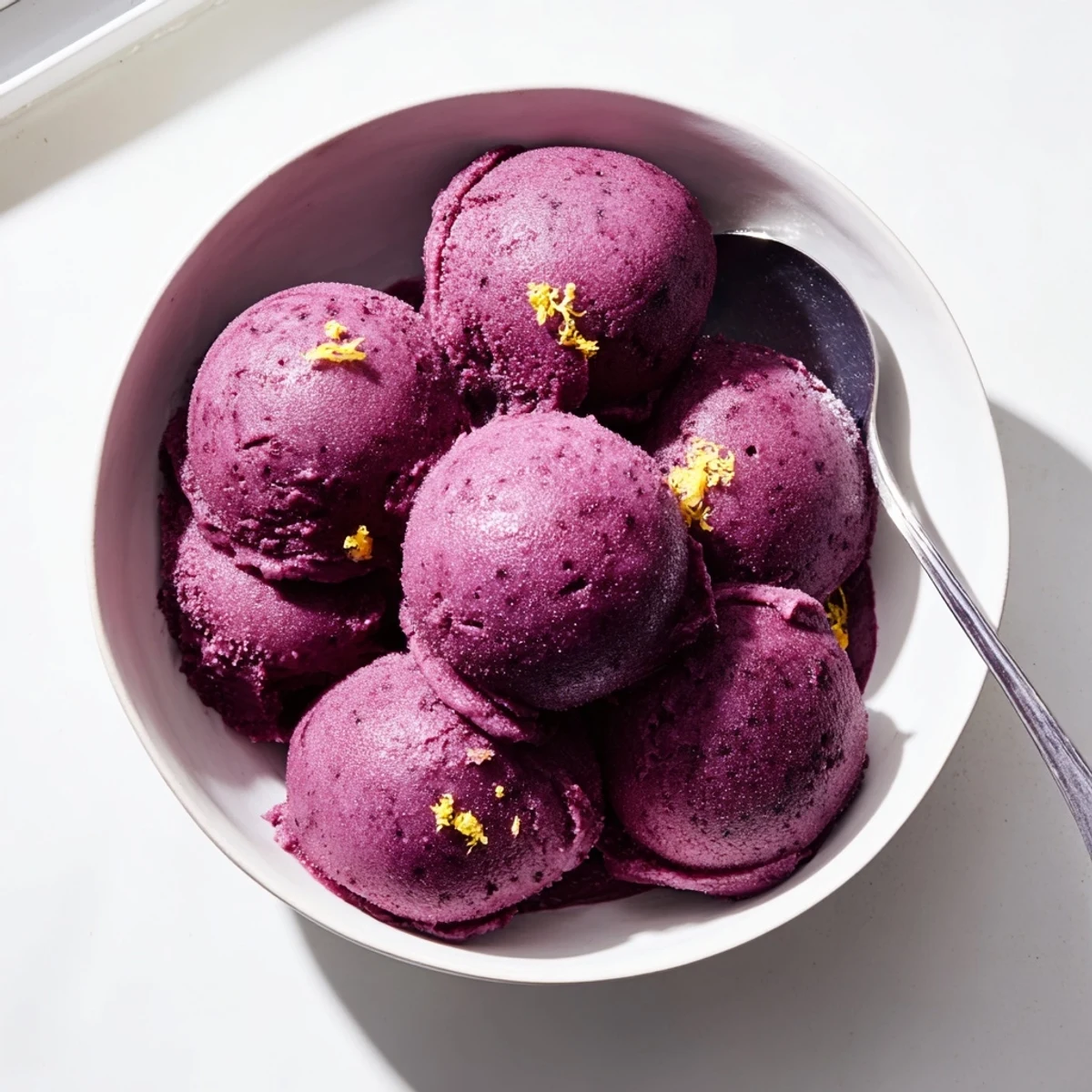 Refreshing scoop of homemade blueberry lemon sorbet garnished with fresh mint leaves and lemon zest