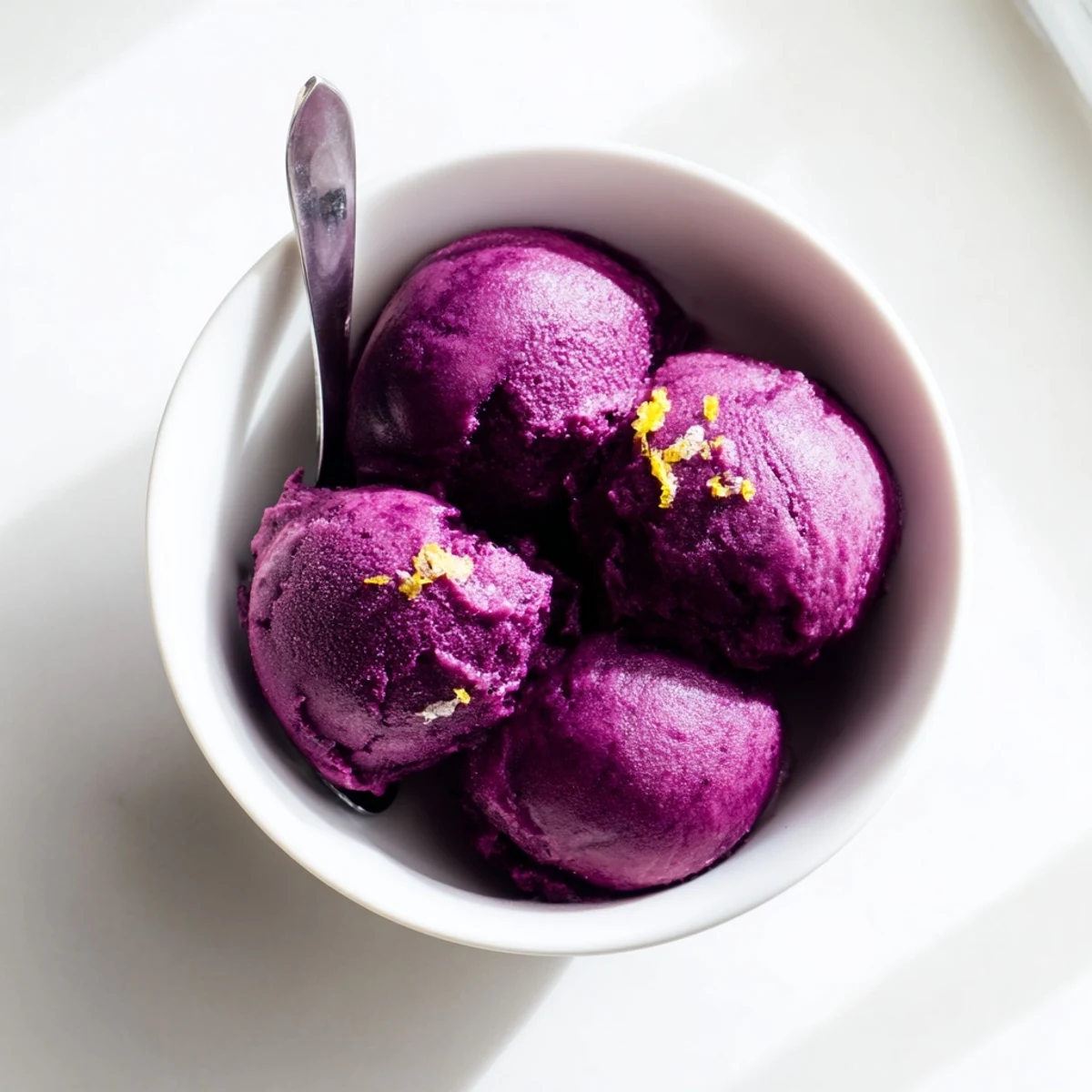 Vibrant berry swirls throughout creamy dairy-free blueberry lemon sorbet in a white serving dish
