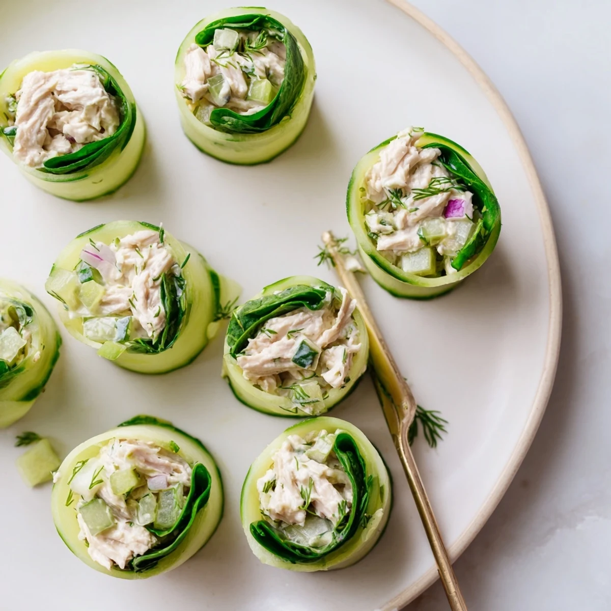 Crisp cucumber rolls filled with seasoned chicken salad served on white platter