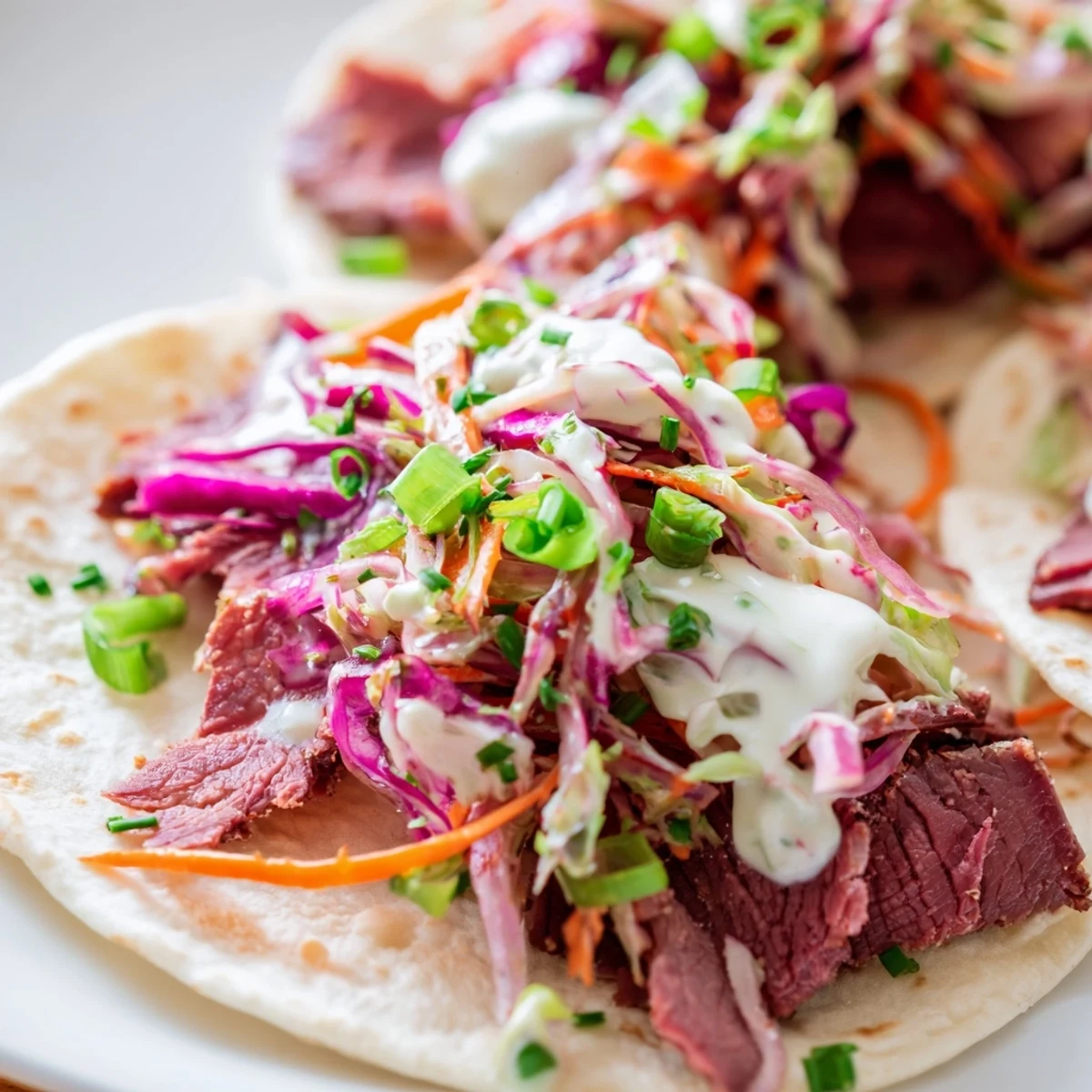 Golden brown corned beef tacos piled with crisp cabbage slaw and creamy horseradish sauce on warm flour tortillas