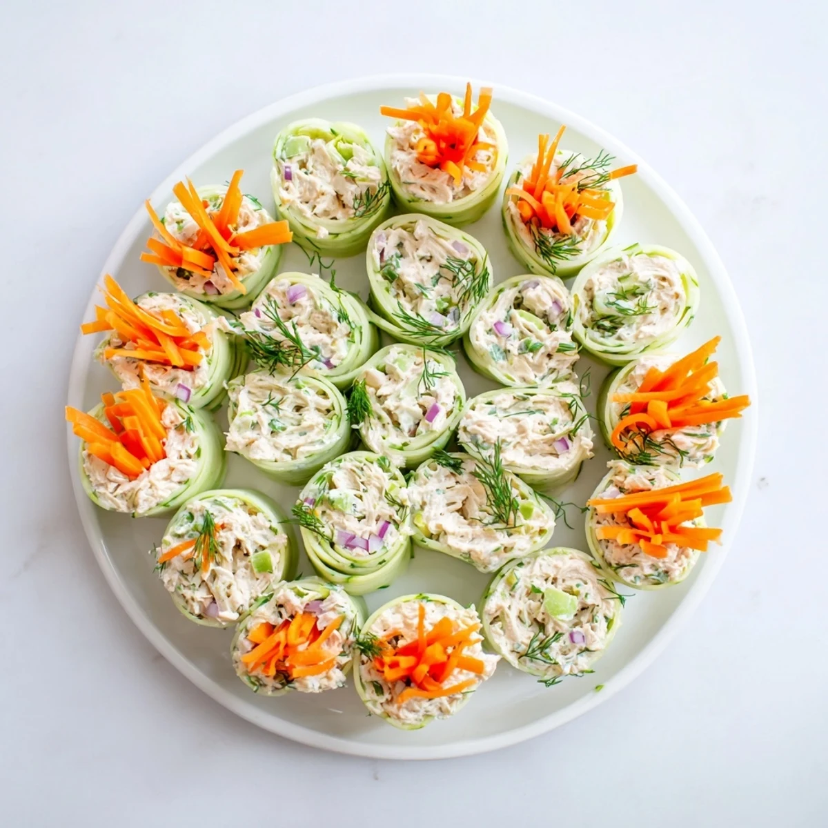 Creamy chicken salad tucked inside cool cucumber ribbons creates refreshing bite-sized appetizers.