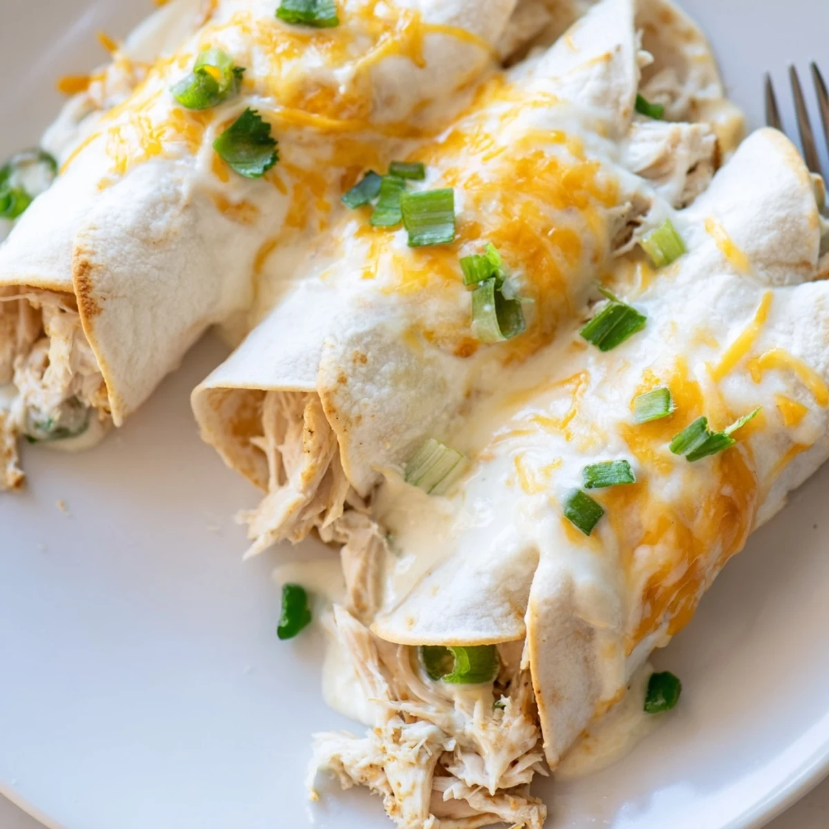 Savory White Rotisserie Chicken Enchiladas sliced on plate, steam rising, ready-to-eat.