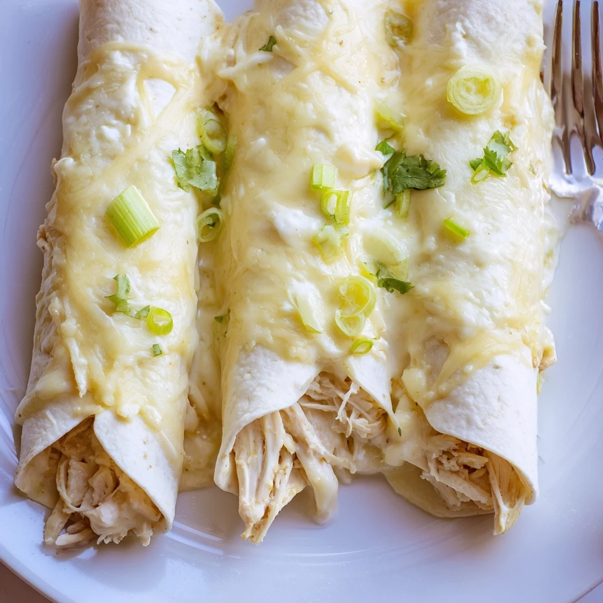 Creamy White Rotisserie Chicken Enchiladas bubbling in a casserole, garnished with cilantro.