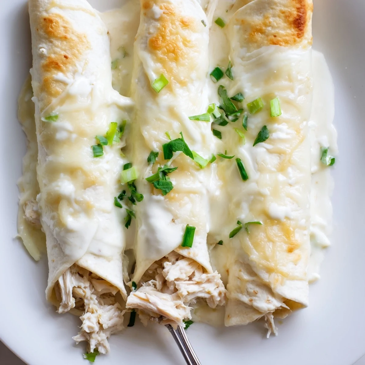 Stack of warm White Rotisserie Chicken Enchiladas with melted Monterey Jack and cilantro