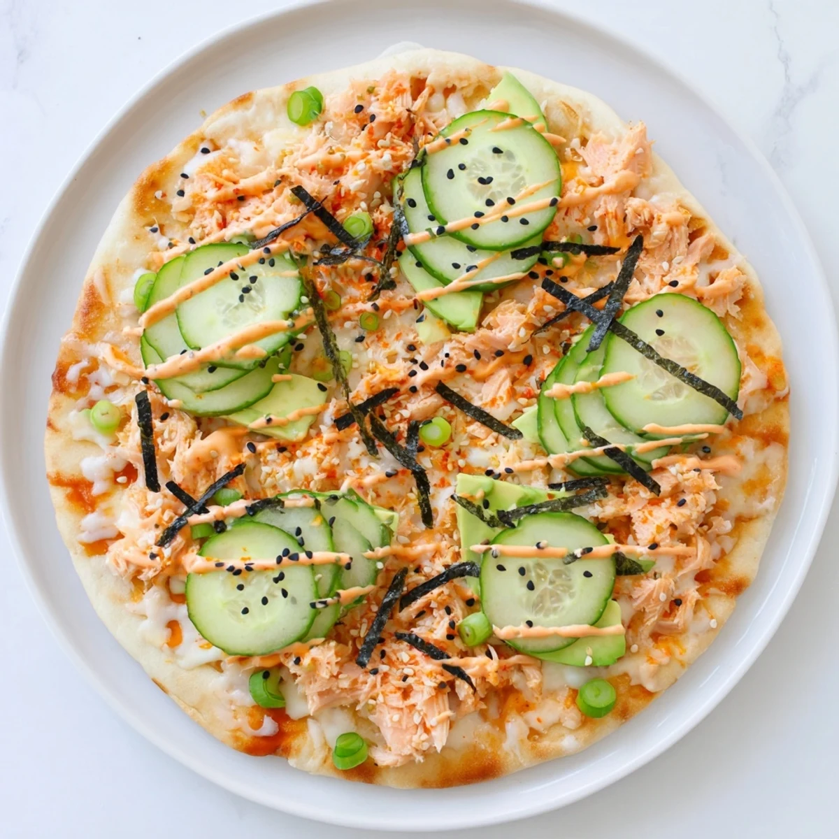 Crispy flatbread loaded with creamy salmon sushi rice mixture melted mozzarella and cucumber strips finished with spicy sauce