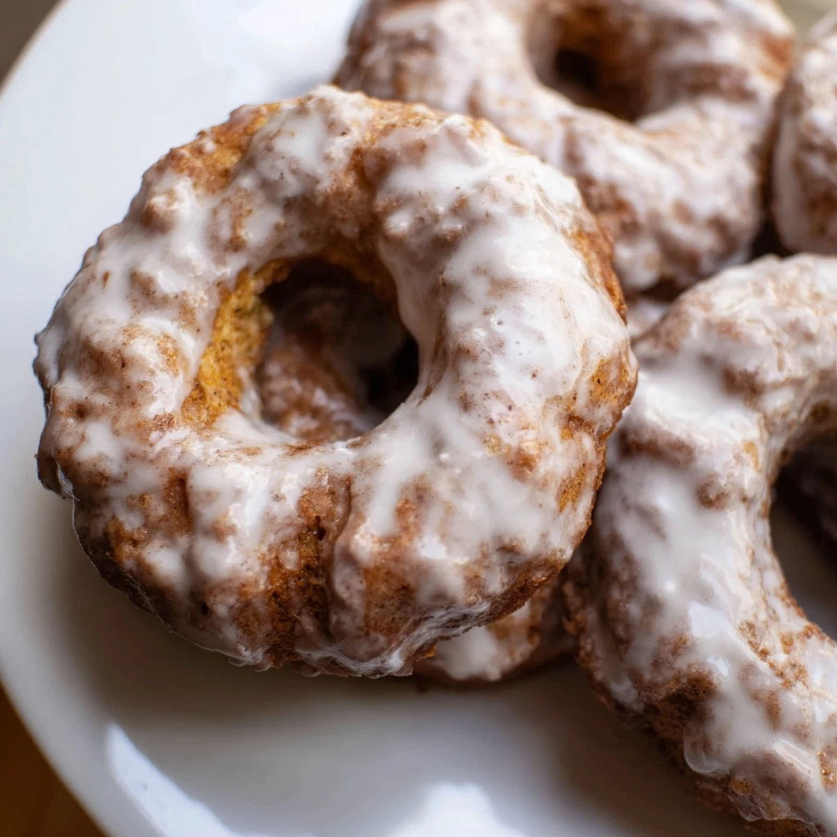 Soft baked banana bread donuts with powdered sugar drizzle cooling on wire rack