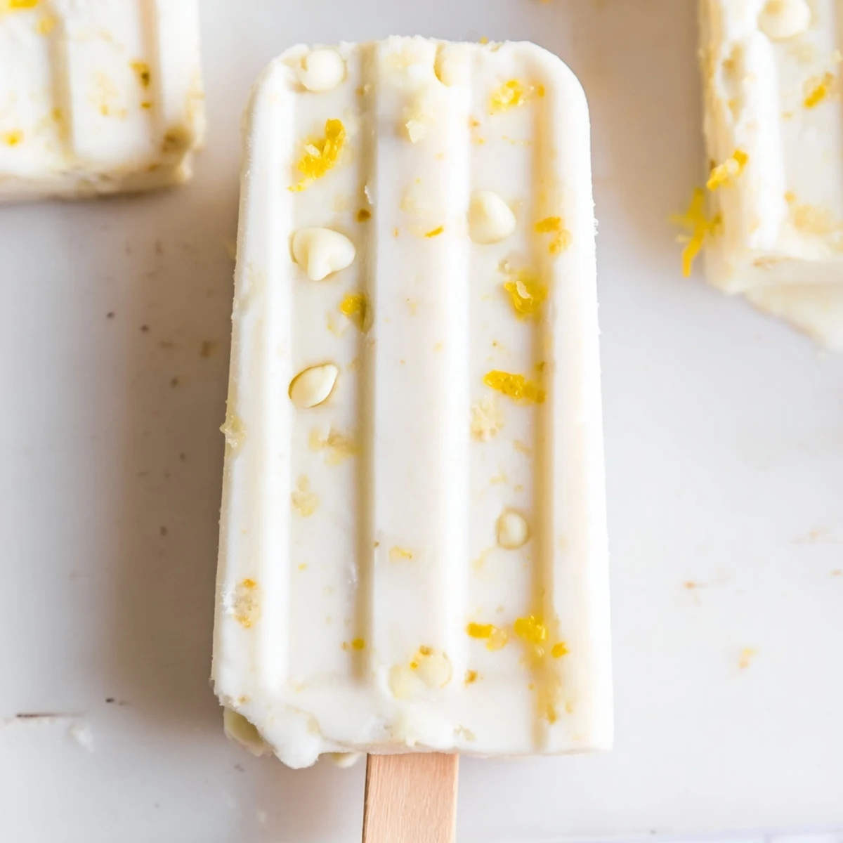 Golden frozen lemon yogurt popsicles dripping with tangy citrus flavor on wooden sticks