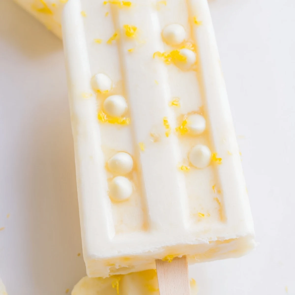 Bright yellow zesty frozen popsicles garnished with mint leaves against a sunny background