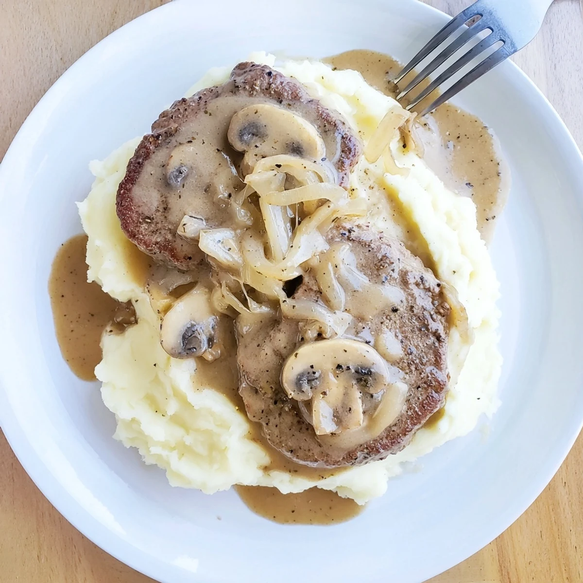 Country Style Smothered Cube Steak Recipe on plate, glossy gravy over mashed potatoes