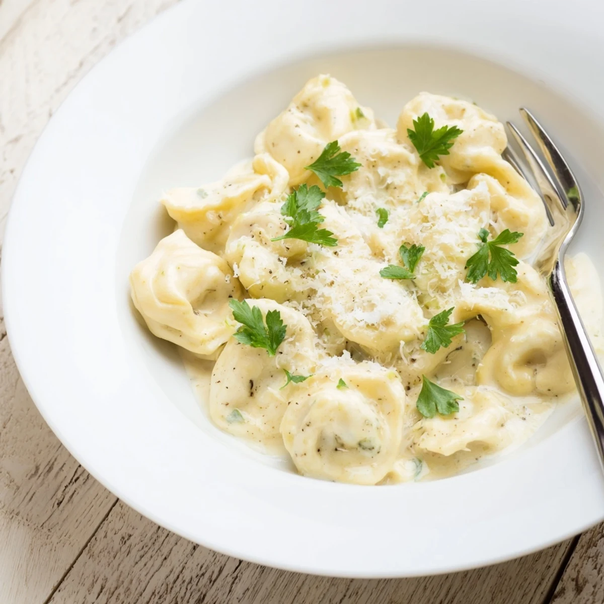 Golden chicken tortellini floating in a rich parmesan cream sauce with fresh parsley.